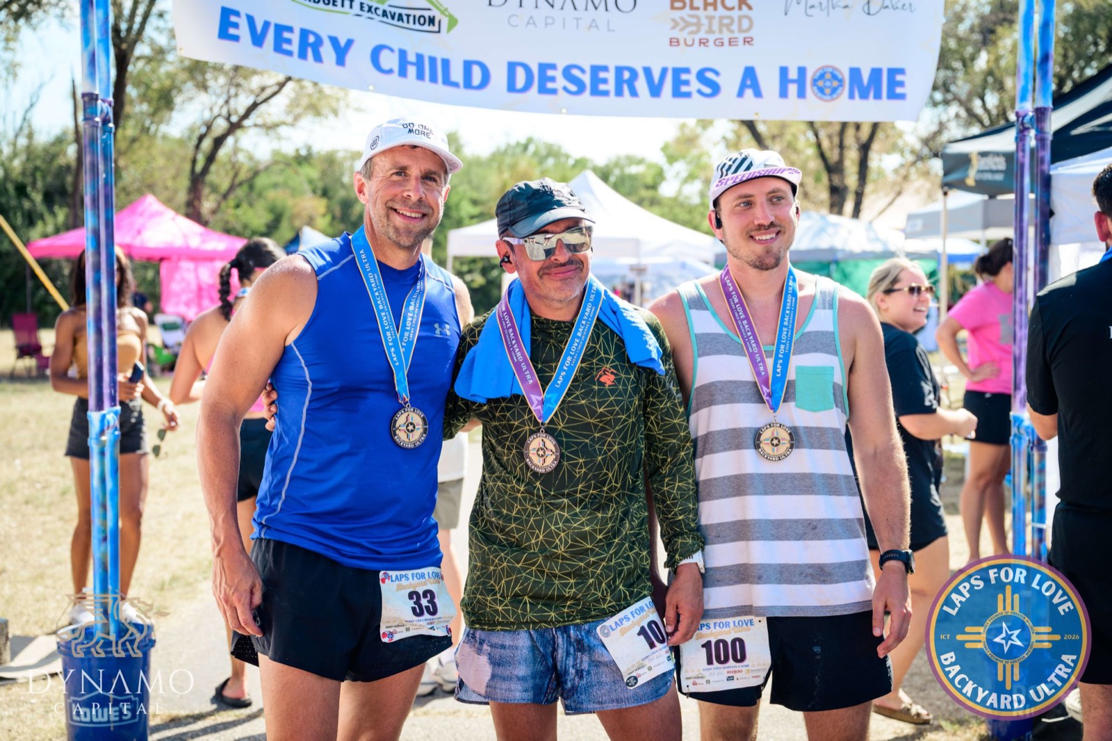 Three runners with their medals under the finish banner